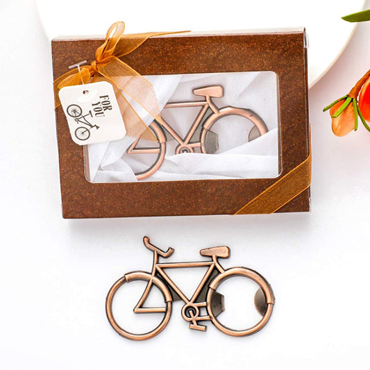 A bicycle-shaped metal object, likely a candle holder or decorative accessory, shown both outside its brown gift box and placed in front. The box has a clear window, a white tag reading 'Fork.
